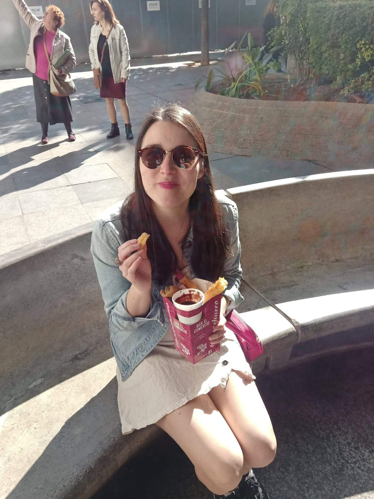 woman sitting on a bench eating churros